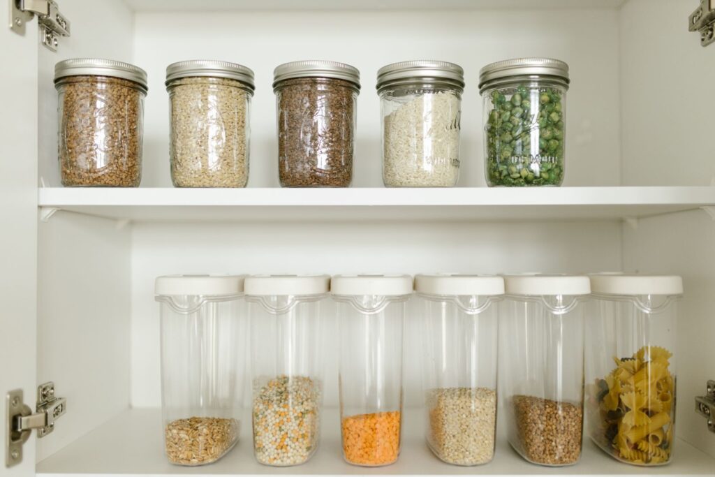 Pantry shelves stocked with glass jars of grains, lentils and pasta